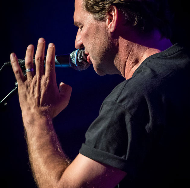 Male performer singing with purple lighting