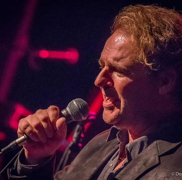 Performer singing with pink stage lighting